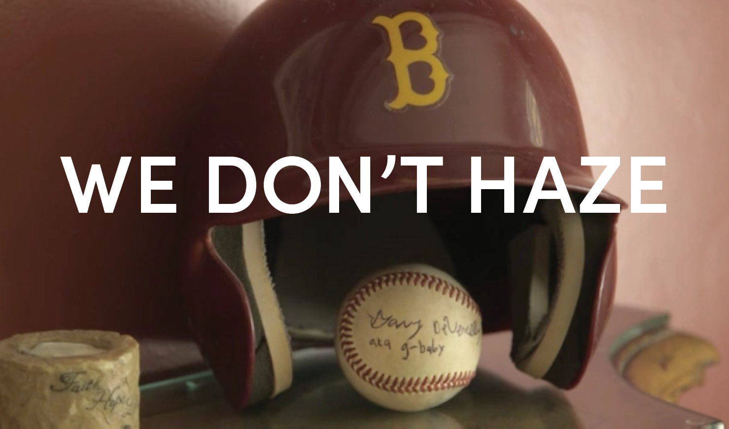 Image of a baseball helmet and ball with overlaid text, which reads "We Don't Haze"